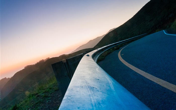 Asphalt road, fence, mountains, dusk Wallpapers Pictures Photos Images
