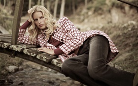 Blonde girl lying on wood bridge, coat