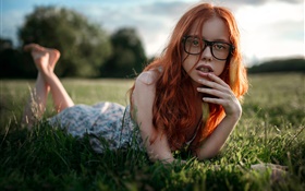Red hair girl lying grass, glasses